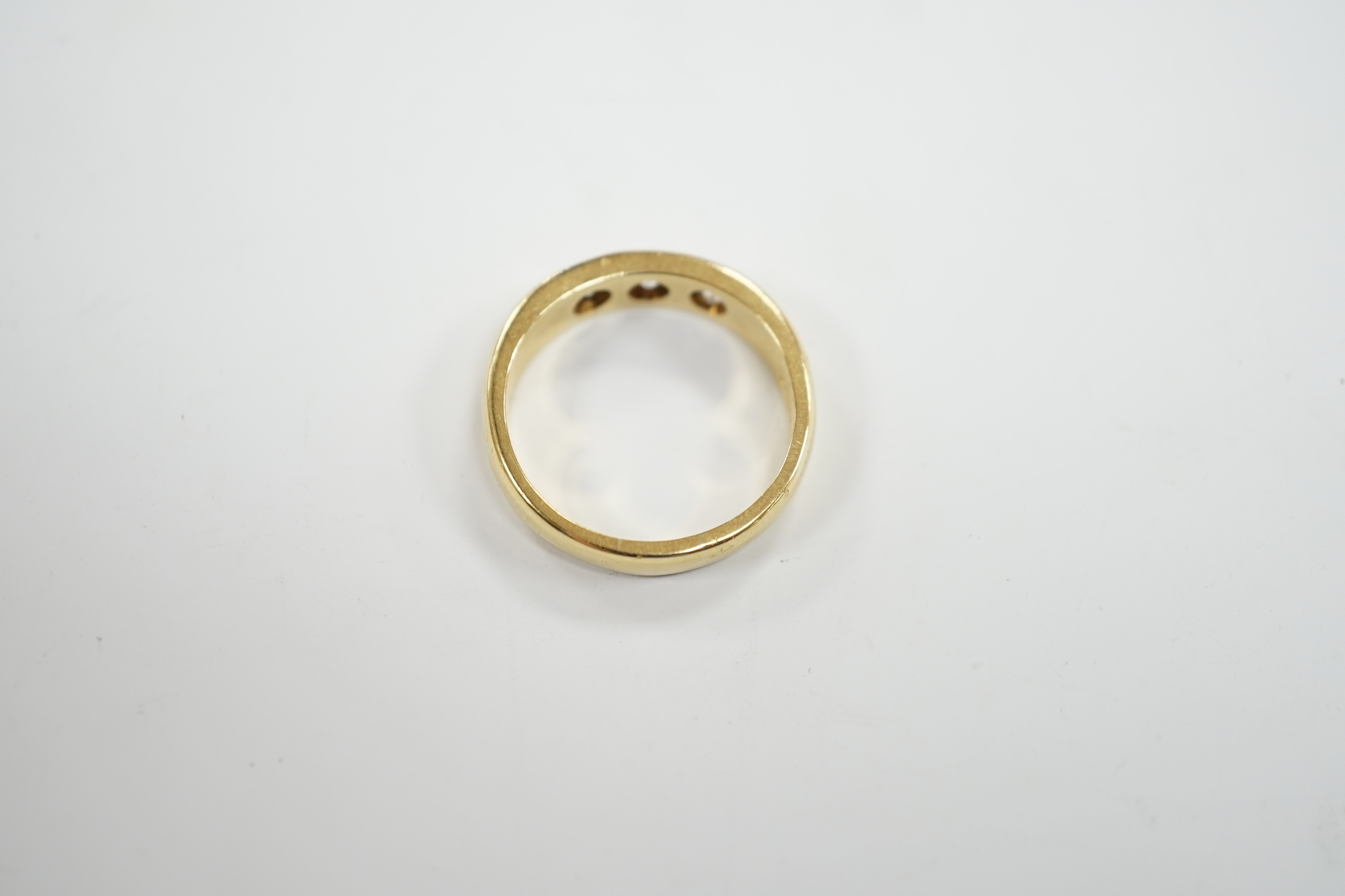 A modern 18ct gold and gypsy set three stone diamond ring, size R, gross weight 7.6 grams.